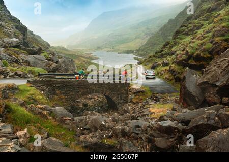 County Kerry, Republik Irland. Irland. Zwei Radfahrer und Auto am Gap of Dunloe oder Bearna an Choimín. Bergpass zwischen Macgillycuddy's Reeks Stockfoto