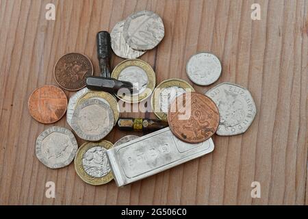 Ein Stapel britischer Münzen mit Bohrern und einer Sterling-Silberklammer, Sterling Stockfoto