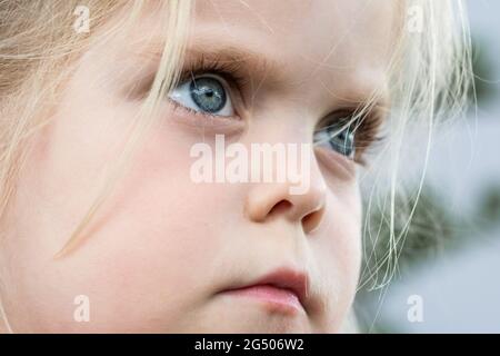 Nahaufnahme des Gesichts und der blauen Augen eines schönen blonden Mädchens, das trotzig aussieht Stockfoto