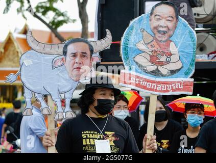 Ein prodemokratischer Protestler der Gruppe United People for Thailand (UPT) trägt eine Gesichtsmaske und zeigt ein Parodie-Porträt des thailändischen Premierministers Prayuth Chan O-Cha (L) und seines Stellvertreters Prawit Wongsuwan, Während einer Kundgebung für die Demokratie, bei der der thailändische Premierminister Prayuth Chan O-Cha zum Rücktritt in Bangkok aufgefordert wurde. (Das Wort lautet Abbrechen Prayuth Chan O-Cha). Stockfoto