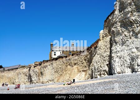 Alte Cottages, die aufgrund der starken Küstenerosion an der Klippe von Birling Gap in der Nähe von Eastbourne East Sussex England, Großbritannien, liegen Stockfoto