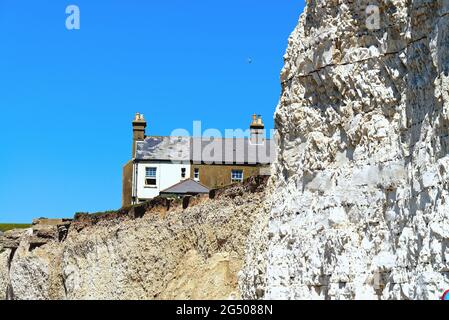 Alte Cottages, die aufgrund der starken Küstenerosion an der Klippe von Birling Gap in der Nähe von Eastbourne East Sussex England, Großbritannien, liegen Stockfoto