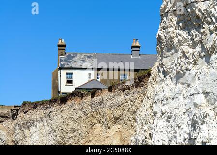 Alte Cottages, die aufgrund der starken Küstenerosion an der Klippe von Birling Gap in der Nähe von Eastbourne East Sussex England, Großbritannien, liegen Stockfoto