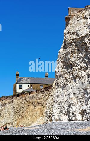 Alte Cottages, die aufgrund der starken Küstenerosion an der Klippe von Birling Gap in der Nähe von Eastbourne East Sussex England, Großbritannien, liegen Stockfoto