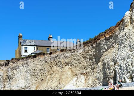 Alte Cottages, die aufgrund der starken Küstenerosion an der Klippe von Birling Gap in der Nähe von Eastbourne East Sussex England, Großbritannien, liegen Stockfoto