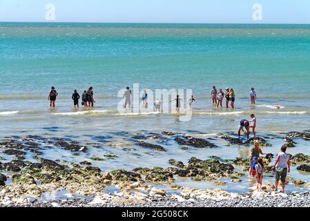 An einem heißen, sonnigen Sommertag in der Nähe von Eastbourne East Sussex England, Großbritannien, paddeln die Menschen am Strand von Birling Gap vorbei Stockfoto