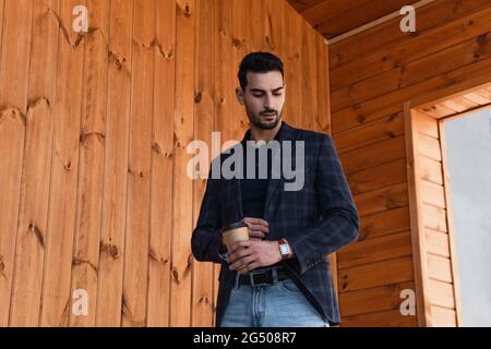 Muslimischer Geschäftsmann mit Kaffee, um die Armbanduhr im Freien zu betrachten Stockfoto