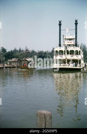 Disneyland, Kalifornien, 1959. Das Mark Twain Riverboat liegt an der Frontierland-Landung auf Rives of America, während das Mike Fink-Kielboot ‘Gullywumper’ vorbeifährt und sich Catfish Cove, Tom Sawyers Insel, nähert. Stockfoto