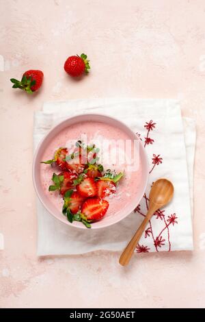 Frühstück mit Müsli, Kokosnuss und Erdbeer Smoothie in einer Schüssel auf einem rosa hellen Hintergrund. Frühling Diät-Menü.Draufsicht. Stockfoto