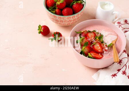 Frühstück mit Müsli, Kokosnuss und Erdbeer Smoothie in einer Schüssel auf einem rosa hellen Hintergrund. Frühling Diät-Menü.Draufsicht. Stockfoto