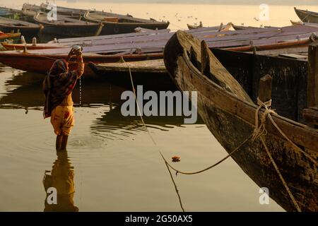 02. FEBRUAR 2021, VARANASI, UTTAR PRADESH, INDIEN - nicht identifizierte Frau, die im Fluss Ganga ein rituelles Bad nimmt und ein Ritual (Puja) im Fluss macht. Stockfoto