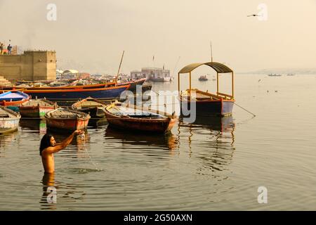 VARANASI, UTTAR PRADESH, INDIEN - Indischer Mann, der am Ganges-Fluss in Varanasi, Uttar Pradesh, Indien, badet und Opfergaben macht Stockfoto