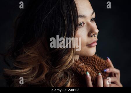 Seitenansicht einer jungen zufriedenen, trendigen Frau. Sie posiert für die Kamera. Stockfoto