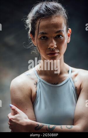 Porträt einer jungen Frau, die in einem Fitnessstudio auf die Kamera schaut. Sie trägt Sportkleidung und schwitzt nach einem Training. Stockfoto