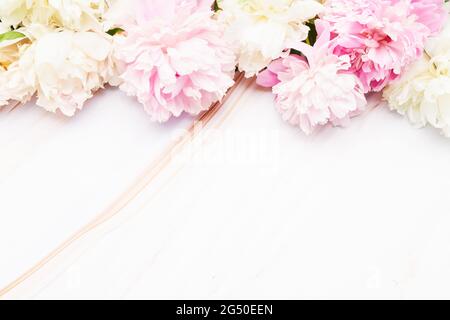 Florale Bordüre aus rosa und weißen Pfingstrosen Blütenknospen auf weißem Marmor Hintergrund. Konzept für Valentinstag, Muttertag und Geburtstagsfeier. Stockfoto