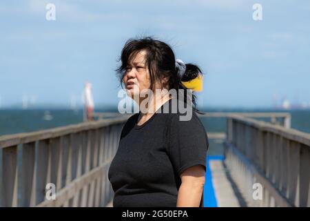 Eine asiatische Frau mittleren Alters auf einem Steg mit blauem Ozean und Himmel im Hintergrund. Bild aus der Grafschaft Scania, Schweden Stockfoto