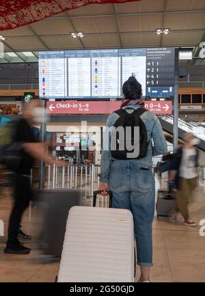 Berlin, Deutschland. Juni 2021. Eine Frau steht vor einer Anzeigetafel im Terminal des Flughafens Berlin-Brandenburg (BER). Der Beginn der Sommerferien führte zu weniger Menschenmengen am Flughafen als erwartet. An den Check-in-Schaltern und Sicherheitskontrollen ging es am Donnerstagmorgen schnell. Quelle: Christophe Gateau/dpa/Alamy Live News Stockfoto