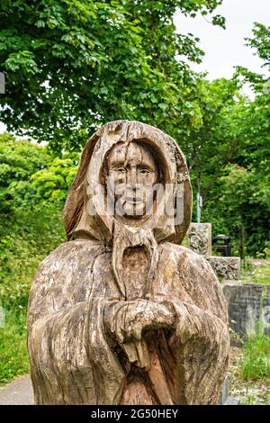 Kettensägen-Schnitzwerk von Fisherman's Wife (gegenüber ihrem Mann stehend) von Tim Burgess auf dem Holy Trinity Churchyard, Morecambe, Lancashire Stockfoto