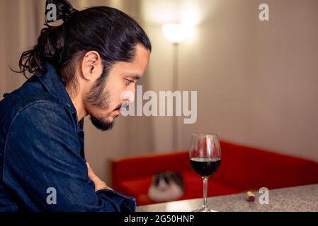 Junger latein deprimiert trinken Rotwein zu Hause im Wohnzimmer Stockfoto