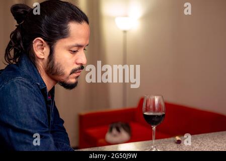 Junger latein deprimiert trinken Rotwein zu Hause im Wohnzimmer Stockfoto