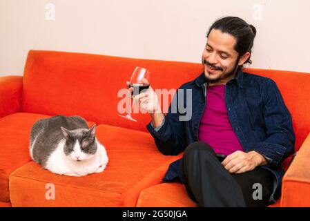 Junger latein trinkt zu Hause im Wohnzimmer Rotwein Stockfoto