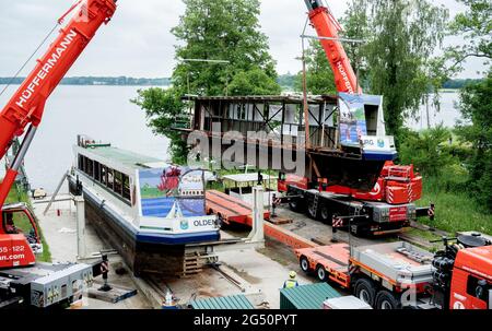 Bad Zwischenahn, Deutschland. Juni 2021. Zwei Mobilkrane heben einen in Längsrichtung geschnittenen Teil des Passagierschiffs „MS Oldenburg“ auf einen Tieflader am Zwischenahner Meer. Das ehemalige Passagierschiff soll per Schwerlastfahrzeug von Bad Zwischenahn aus nach Oldenburg transportiert werden. Dort wird es später als Restaurantschiff im Stadthafen eingesetzt. Quelle: Hauke-Christian Dittrich/dpa/Alamy Live News Stockfoto