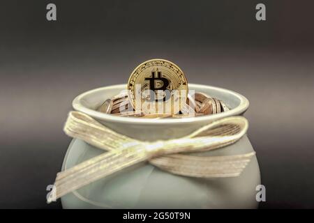Die Bitcoin-Münze liegt im Sparschwein auf fiat-Münzen. Akkumulation von Kryptowährungen und Investitionssymbol Stockfoto