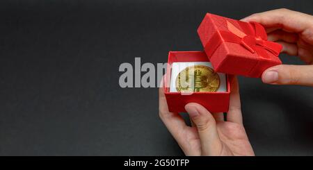 Bitcoin Münze in Geschenkbox für Ring oder Kryptowährung Schmuck Konzept, Bestes Geschenk. weihnachten und Neujahr Geschenk. Hände öffnen Geschenkbox mit Bitcoin Münze Stockfoto