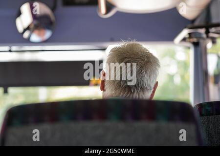 Älterer Mann, der im Reisebus unterwegs ist, Blick von hinten nur auf seinen grauen Haarkopf Stockfoto
