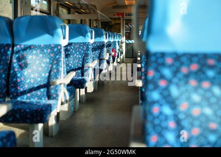 Sonne scheint auf leeren Sitzen im Zug, abstraktes Bahnfahrkonzept mit geringer Schärfentiefe Foto nur wenige Stühle fokussieren Stockfoto