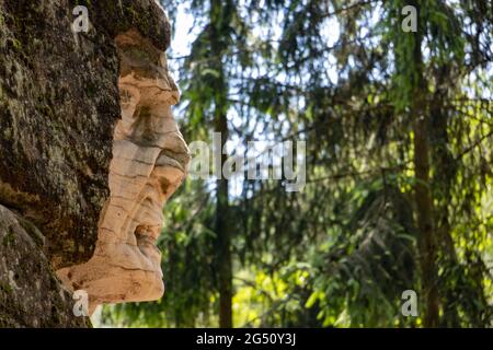 NORDBÖHMEN, TSCHECHIEN, JUNI 06 2021, gruseliger Kopf, der in einem Wald in den Fels gehauen wurde. Stockfoto