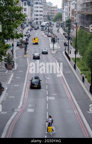 Eine einreisende Frau mit einem gelben Koffer überquert am 24. Juni 2021 in London, England, die Farringdon Road in der City of London, dem Finanzdistrikt der Hauptstadt. Stockfoto