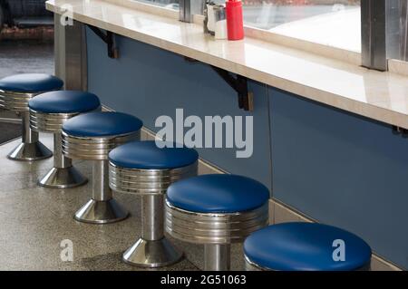 Vintage Diner Hocker in einem alten Diner aus den 1950er Jahren mit blauen Vinylsitzen. Stockfoto