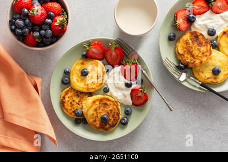 Quark Pfannkuchen mit Erdbeeren, Heidelbeeren und saurer Rahm, Becher mit Milch und frischen Beeren, leckeres Frühstück, Blick von oben Stockfoto
