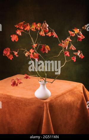 Stillleben im Herbst mit einem Viburnum-Zweig in einer weißen Vase Stockfoto