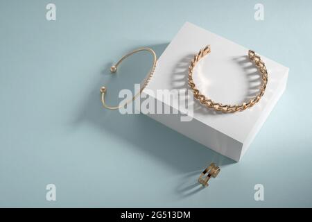 Goldene Armbänder und Ring auf weißer Box auf blauem Hintergrund mit Kopierplatz Stockfoto