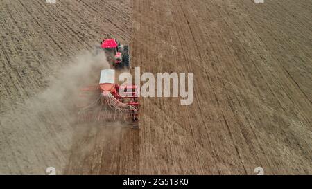 Traktor mit Aggregat verarbeitet staubigen Boden auf der Prärie. Der Bauer sät in den wüsten, leblosen Steppen. Konzept des riskanten Agrargeschäfts. Luftaufnahme Stockfoto