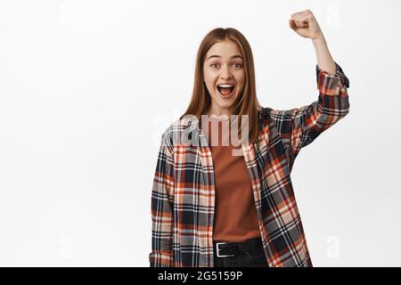 Go Team. Fröhliche junge Frau jubelt, fistelt und singt, wurzelt für dich, ermutigt, lächelt und schaut glücklich, Aktivist pumpt die Menge Stockfoto