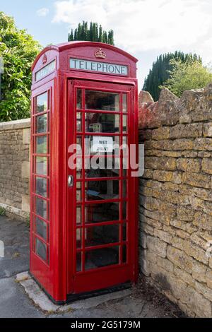 Altmodische rote Telefonzelle mit Nasslackschild, England, Großbritannien Stockfoto