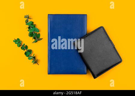 Schwarze und blaue Ledernotizbücher auf dem yyelow Büro-Desktop, Business-Workspace-Konzept mit getrockneten Blumen, flachem Lay und Draufsicht-Foto Stockfoto