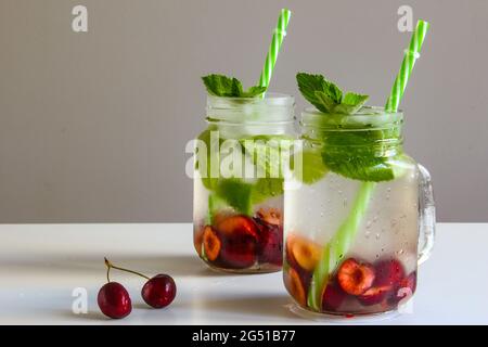 Kalte Getränke in kleinen Flaschen. Kirschen Minzlimonade. Mojito-Coctail. Stockfoto