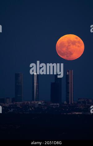 Madrid, Spanien. Juni 2021. Der Vollmond im Juni, der auch als Erdbeermond bekannt ist, steigt über den Wolkenkratzern des Four Towers Business Area in der Innenstadt von Madrid auf. Quelle: Marcos del Mazo/Alamy Live News Stockfoto