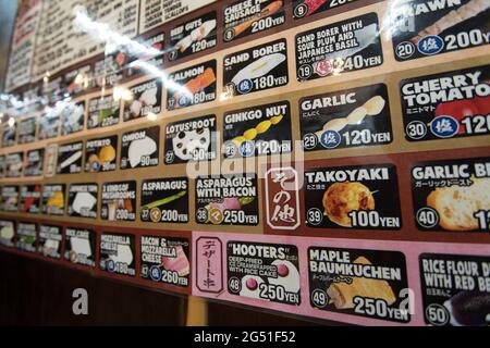 Ein Menü an der Wand eines Yakitori-Restaurants in Osaka, Japan