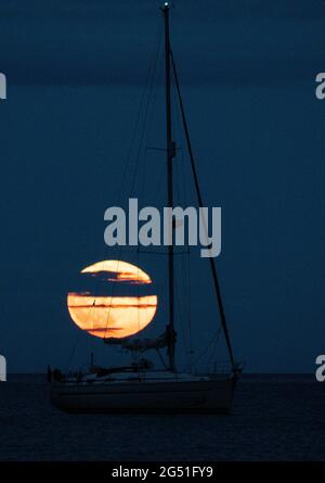 Cawsand Bay, Cornwall, Großbritannien. UK Wetter: 24. Juni 2021. Der Strawberry Full Super Moon steigt am Horizont in der Cawsand Bay mit hellem Himmel auf, um das Spektakel zu sehen © DGDImages/AlamyNews Stockfoto