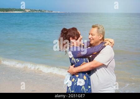 Ein älteres hispanisch-pärchen umarmt sich am Strand Stockfoto
