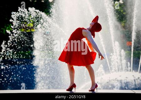 Frau in rotem Kleid, die gegen den Brunnen tanzt Stockfoto