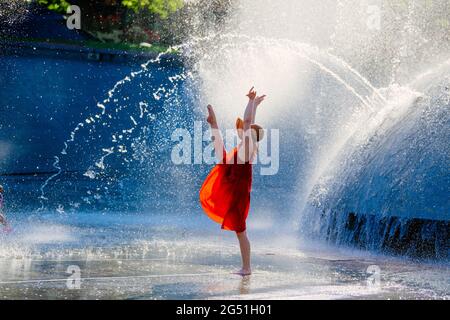 Frau in rotem Kleid, die gegen den Brunnen tanzt Stockfoto