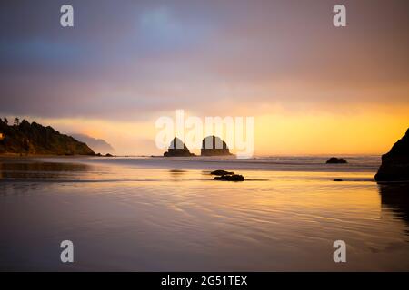 Bei Ebbe schöner, farbenfroher Sonnenuntergang am Cannon Beach, Oregon, mit Blick nach Süden entlang der Küste Stockfoto