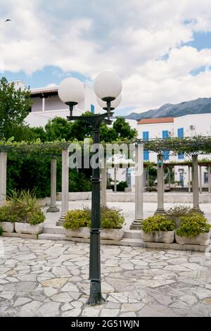 Laterne vor dem Hintergrund einer grünen Terrasse, einem Haus und Büschen in Wannen Stockfoto