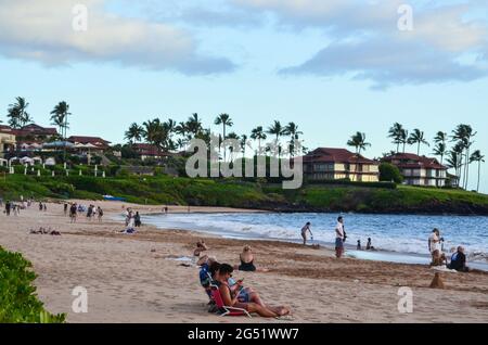 Menschen, die den Sonnenuntergang betrachten, während sie sich am Strand entspannen. Stockfoto